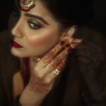 Beautiful muslim bride wearing jewellery and doing her makeup in a delhi wedding