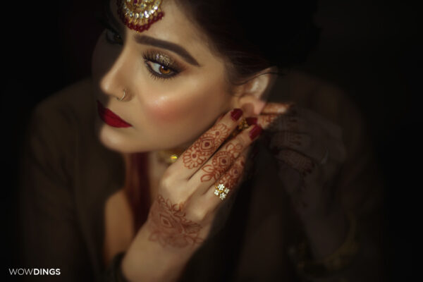 Beautiful muslim bride wearing jewellery and doing her makeup in a delhi wedding