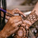 Muslim bride's hands with intricate mehndi designs during a vibrant ceremony