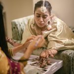 Muslim bride's hands with intricate mehndi designs during a vibrant ceremony