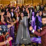 crowd cheering at people dancing on sangeet ceremony at an indian wedding in delhi on engagement day candid photography