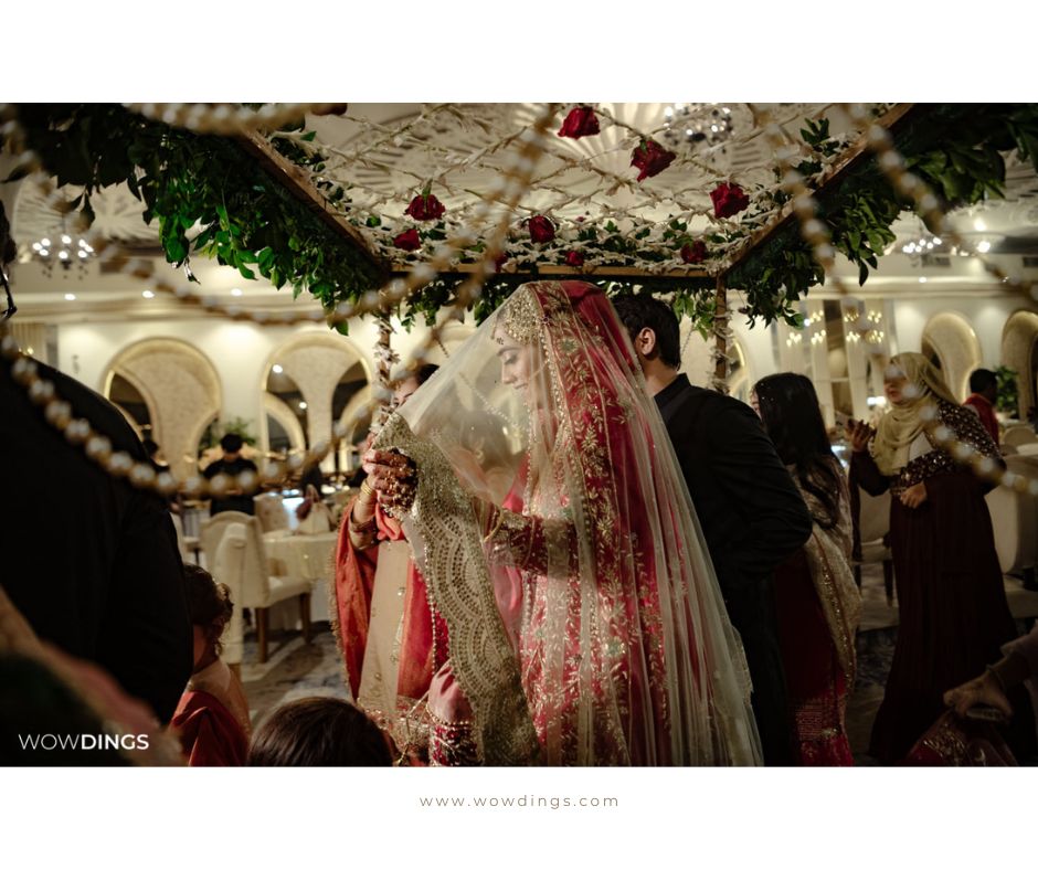 Nikaah: a muslim wedding photography blog 15 bride walking under phoolon ki chadar or a veil of flowers to meet the groom.